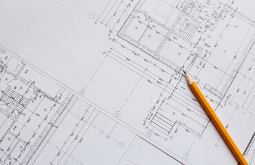 pencil and office tools for writing on the blueprint of construction industry. Place the rolls on a desk over blurred blueprint for construction industry background.