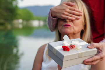 closeup of surprised woman receiving a gift from her girlfriend