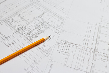 pencil and office tools for writing on the blueprint of construction industry. Place the rolls on a desk over blurred blueprint for construction industry background.