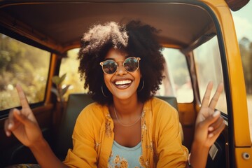 Beautiful smiling girl dressed in hippie style in front of a retro van. Happy Hispanic female tourist traveling through a picturesque tropical country. Travel concept. - obrazy, fototapety, plakaty