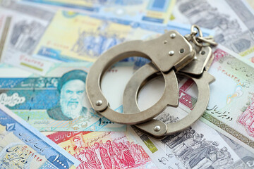Police handcuffs with iranian money bills rials. The concept of crime and offenses or fraud with...