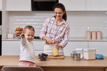 Obraz na płótnie Canvas mother with her little daughter preparing plum pie at kitchen. baking together