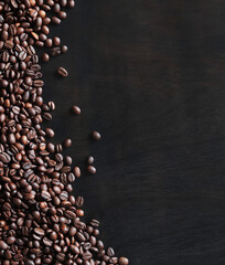 Roasted coffee beans on a wooden dark table, top view. Background of fragrant brown coffee beans...