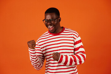 Black man demonstrating success making a winner's gesture with his hands raised, clenched into fists.