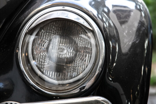 Classic round headlight of an old timer car, front view. Close up