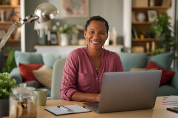 Smiling businesswoman using a laptop in her home office