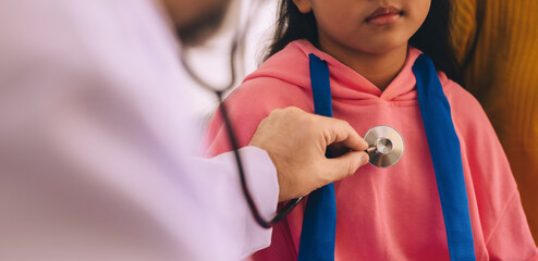 Up close, a young girl is being consulted and examined by a male doctor in the hospital.