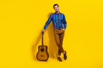 Full size photo of handsome guy dressed striped shirt stand with acoustic guitar arm in pocket...