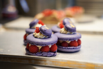 Close up of purple macaron filled with cream and raspberry.