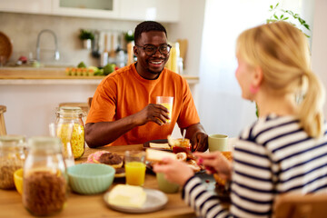 Multiracial couple enjoying breakfast together at home