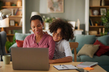 Obraz premium Mother and teenage son using a laptop together at home