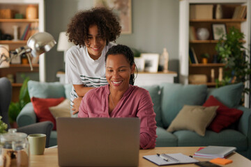 Mother and teenage son using a laptop together at home