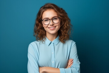 Fototapeta premium Portrait of a smiling young businesswoman with glasses on blue background