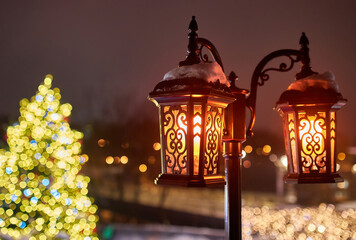 Retro street lantern, lamp with yellow glowing light on building wall with snow, winter decoration...