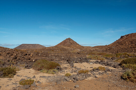 Lavah&uuml;gel mit Sand und Lavasteinen im Vordergrund auf Fuerteventura