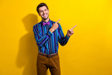 Photo of satisfied cool man dressed striped shirt tie bow indicating at discount empty space isolated on vivid yellow color background