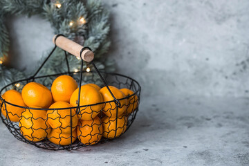 Christmas New Year background with tangerines in a retro metal basket on a gray background. Citrus...