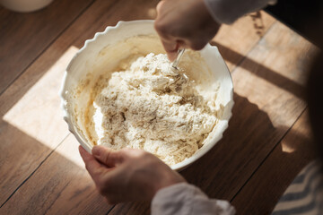 Woman stirring dough in bowl, prepare for bread. Female baking bread at home, kitchen routine
