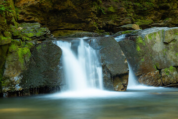 Fototapeta na wymiar Girlish Tears waterfall on Zhonka River in Carpathian Mountains, Ivano-Frankivsk Oblast, western Ukraine. Beautiful tender flow of water between big rocks