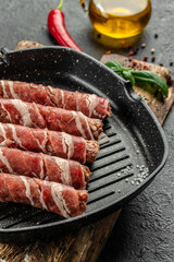 Pork wrapped in bacon in pan on a dark background. vertical image. top view. copy space for text