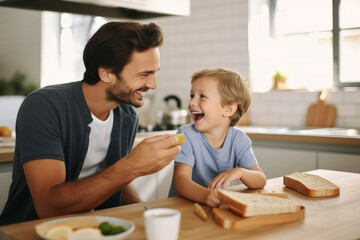 Happy father and son having breakfast together in the kitchen at home.