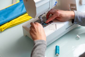 Close up shot of Tailor's female hands preparing sewing machine.