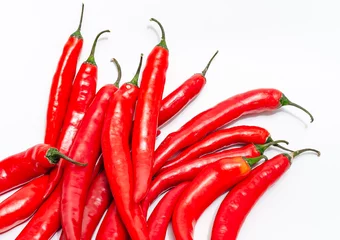 Fotobehang Close up bunch of red chili peppers on white isolated background. Diagonally in lower left corner. © romankrykh