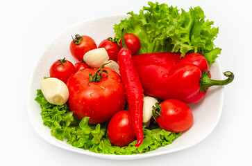 Delicious vegetable salad in bowl with water drops. Tomatoes, lettuce, garlic, chili, sweet pepper.