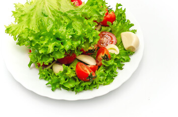 Delicious vegetable salad in a bowl on a white background. Chopped tomatoes, lettuce, garlic.