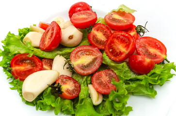 Delicious vegetable salad in a bowl on a white background. Chopped tomatoes, lettuce, garlic, salt.