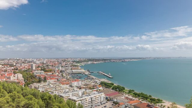 Panorama showing aerial view of marina and city center timelapse in Setubal, Portugal. Red roofs and waterfront with boats and ships from above. Cloudy sky at sunny day