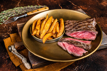 Elk steak with herbs and french fry, game meat. Dark background. Top view