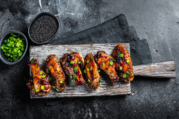 Chicken buffalo wings in sweet and sour sauce with black sesame. Black background. Top view