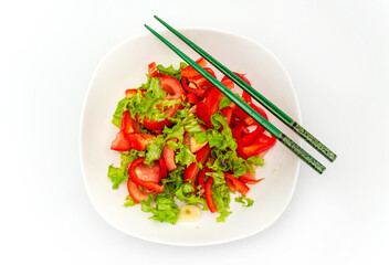 White plate of salad with vegetables isolated on white background. Wooden chopsticks for food.
