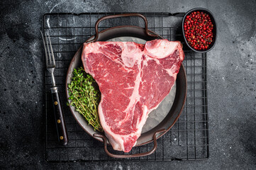 Fresh raw T-bone marbled beef meat Steak on a steel tray. Black background. Top view - obrazy, fototapety, plakaty