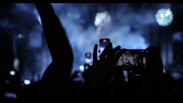 Silhouette of a hand with a mobile phone camera and enjoying the concert