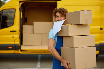 Funny deliveryman carrying pile of cardboard boxes providing professional service
