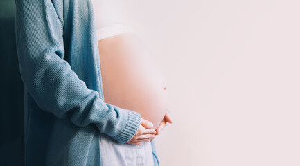 Pregnant woman holds hands on her belly.  Pregnancy, maternity, preparation and expectation concept.