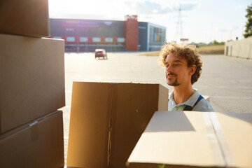 Young warehouse worker holding clipboard box unloading delivery truck