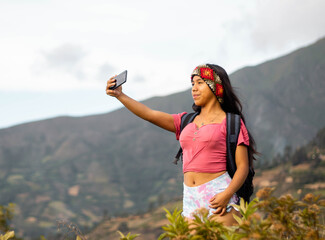 mujer excursionista video llamada con un smartphone en el acantilado de la montaña junto al fondo...
