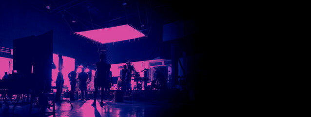 Silhouette of people working in big production studio for shooting or recording movie video by digital camera and lighting set. Video Production Behind the scenes.