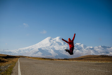 the girl jumps to the top with a view of Elbrus