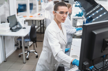 Two female scientists work in a modern equipped computer laboratory analyzing blood samples and genetic materials using special machines in a modern laboratory.