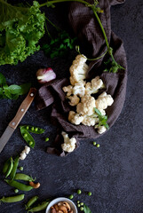 Cauliflower with vegetables and spices on a dark wood background