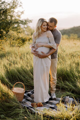 Beautiful young pregnant couple spending time together in outdoor at sunset. The concept of...