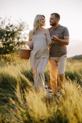 Beautiful young pregnant couple spending time together in outdoor at sunset. The concept of expecting a baby, parenthood.