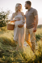 Beautiful young pregnant couple spending time together in outdoor at sunset. The concept of...