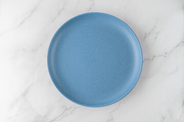 Empty vintage style  blue plate on white marble table background. Cuisine mockup with copy space