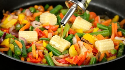 Pouring oil for cooking vegetables in pan. Healthy food, vegetarian cuisine