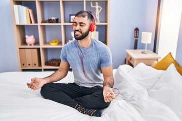 Young hispanic man doing yoga exercise sitting on bed at bedroom